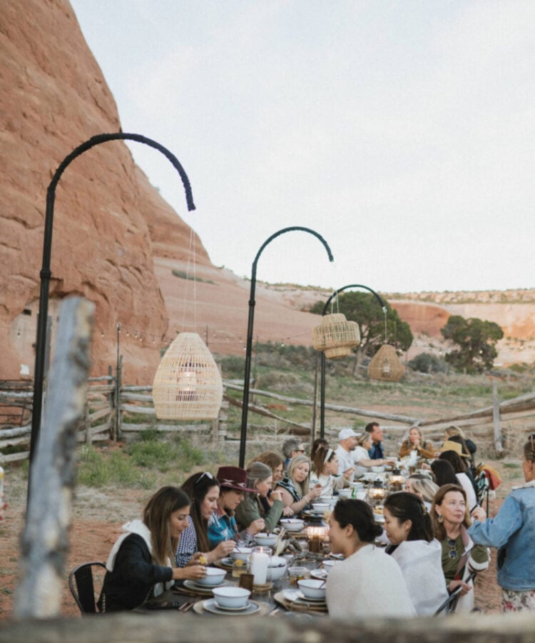 An event being hosted at ULUM Moab where a group has dinner around a long table surrounded by Moab desert scenery.