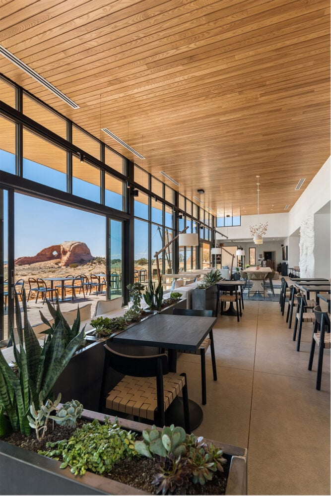 A dining area with large windows, wooden ceiling, and plants