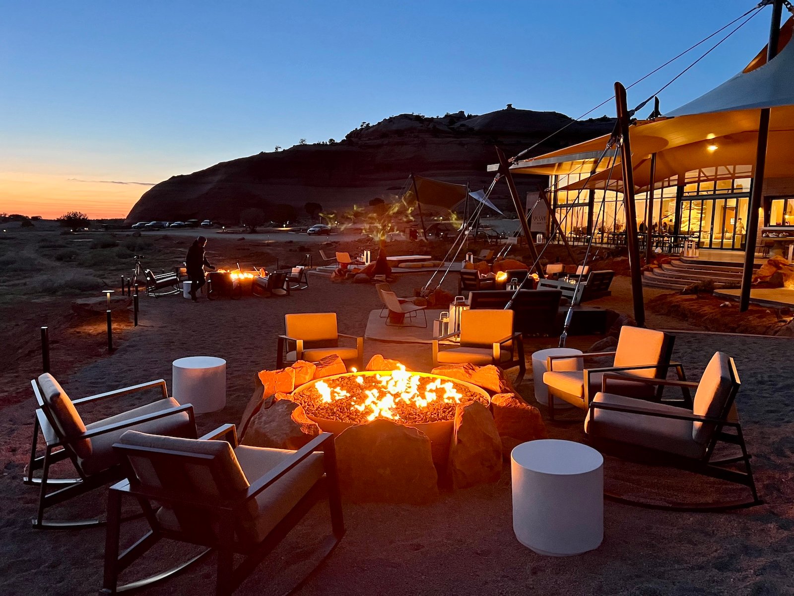 A sunset campfire at ULUM Moab, a luxury resort in Moab, Utah in front of the resort's upscale lobby tent.