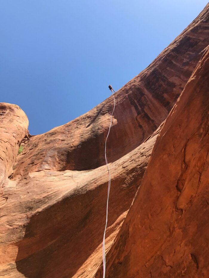 Rock Climber repelling down a canyon in Moab