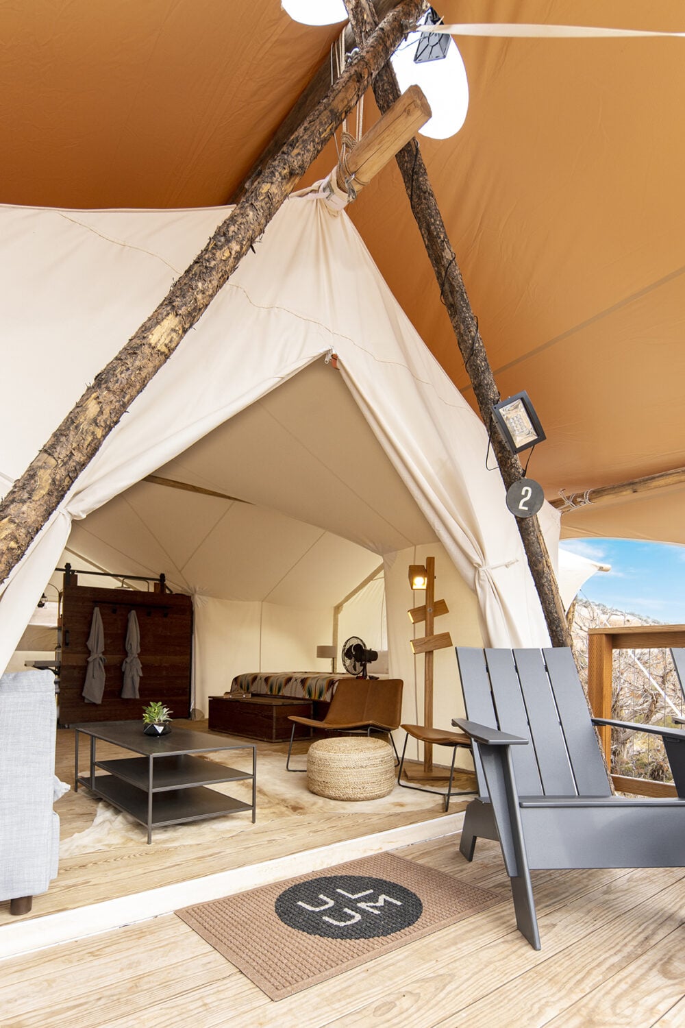 A wide view of a glamping tent with furniture and decor, and a mountain view outside.