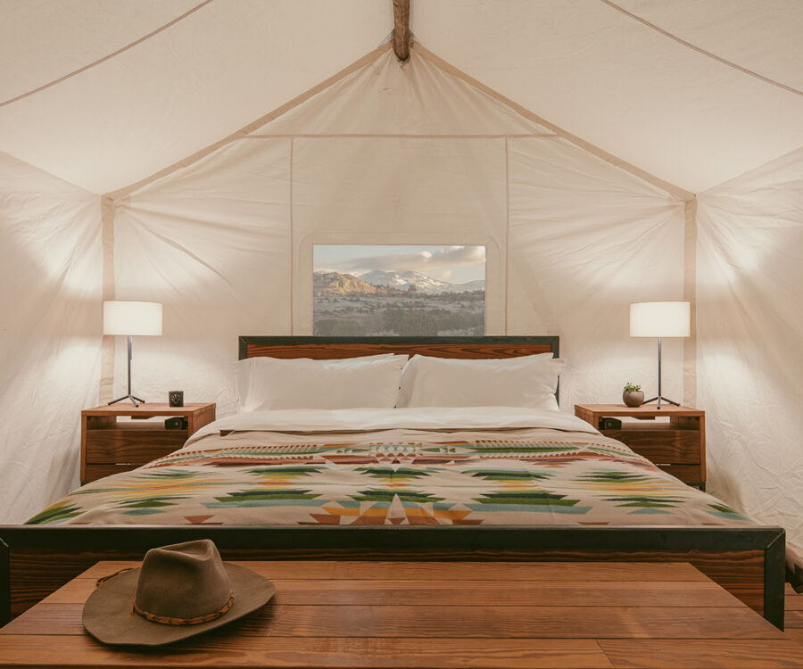View of king sized bed featuring parachute linens and a pendleton wool blanket