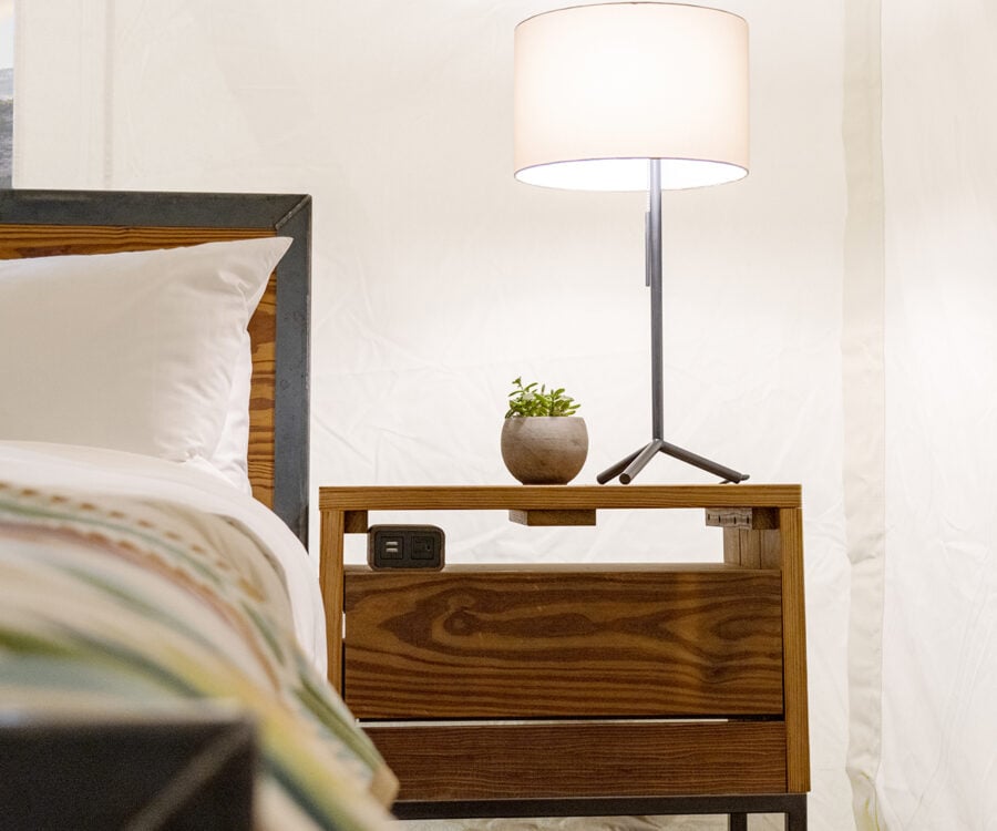 View of king sized bed featuring parachute linens and a pendleton wool blanket