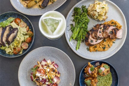 A table with plates of Southwest-inspired cuisine and drinks from ULUM Moab's full-service restaurant.