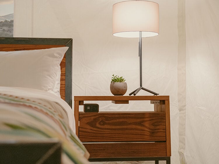 View of king sized bed featuring parachute linens and a pendleton wool blanket