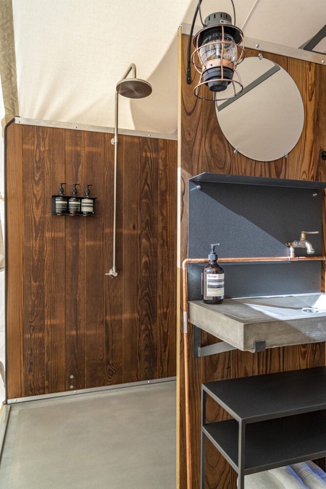A modern bathroom with a shower, concrete sink, and wood paneling